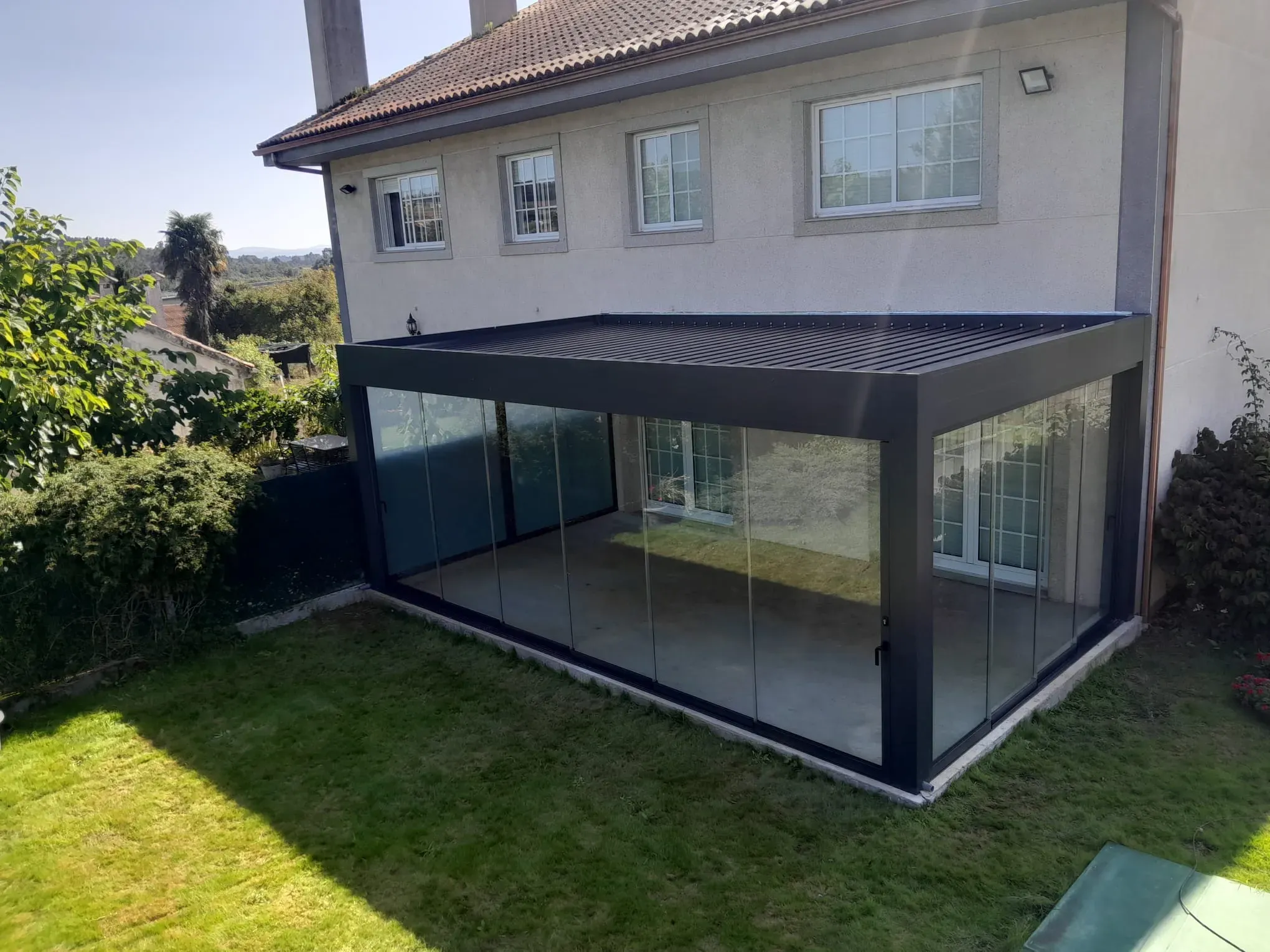 Pérgola bioclimática con lamas orientables filtrando la luz natural sobre una terraza